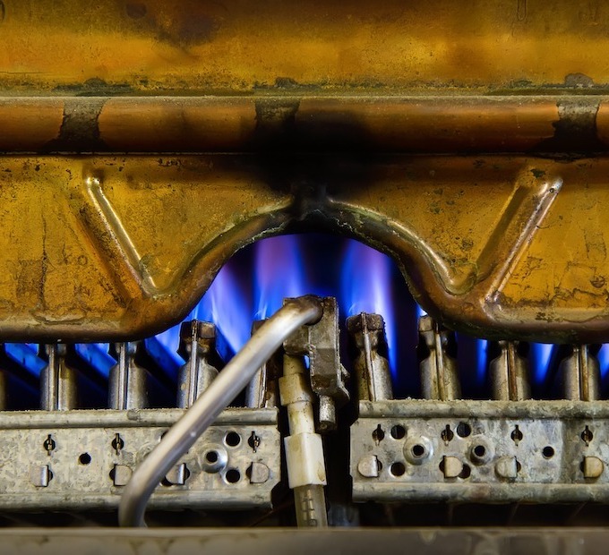 A gas furnace is depicted, blue flames are apparent.